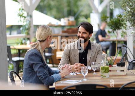 Pärchen sitzen draußen auf dem Terrassenrestaurant und haben ein Dinner-Date. Geschäftsessen für zwei Manager, Besprechung des neuen Geschäftsprojekts. Stockfoto