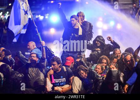 Tel Aviv, Israel. März 2024. Die Wasserkanonen der Polizei besprühen israelische Demonstranten, während sie die Ayalon-Autobahn während der Demonstration blockieren. Tausende Israelis protestierten gegen Premierminister Benjamin Netanjahu und seine rechtsextreme Regierung, die eine sofortige Freilassung von Geiseln und allgemeine Wahlen im Staat Israel forderten. Während der Demonstration durchbrachen Demonstranten die israelischen Polizeibarrieren und es kam zu Auseinandersetzungen zwischen der Polizei und den Demonstranten. (Credit Image: © Matan Golan/SOPA Images via ZUMA Press Wire) NUR REDAKTIONELLE VERWENDUNG! Nicht für kommerzielle ZWECKE! Stockfoto