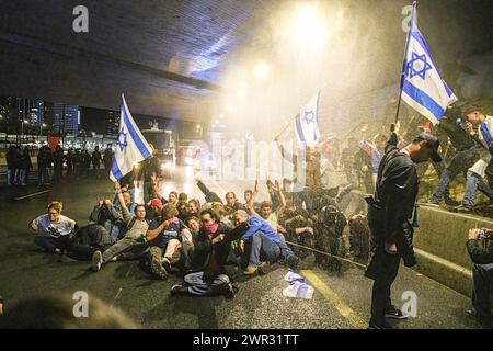 Tel Aviv, Israel. März 2024. Demonstranten blockieren den Ayalon Highway, da die Polizei Wasserwerfer benutzt, um sie während der Demonstration zu zerstreuen. Tausende Israelis protestierten gegen Premierminister Benjamin Netanjahu und seine rechtsextreme Regierung, die eine sofortige Freilassung von Geiseln und allgemeine Wahlen im Staat Israel forderten. Während der Demonstration durchbrachen Demonstranten die israelischen Polizeibarrieren und es kam zu Auseinandersetzungen zwischen der Polizei und den Demonstranten. (Credit Image: © Matan Golan/SOPA Images via ZUMA Press Wire) NUR REDAKTIONELLE VERWENDUNG! Nicht für kommerzielle ZWECKE! Stockfoto