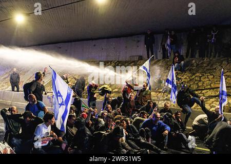 Tel Aviv, Israel. März 2024. Ein Journalist wird während der Demonstration direkt von einer Wasserkanone der Polizei getroffen. Tausende Israelis protestierten gegen Premierminister Benjamin Netanjahu und seine rechtsextreme Regierung, die eine sofortige Freilassung von Geiseln und allgemeine Wahlen im Staat Israel forderten. Während der Demonstration durchbrachen Demonstranten die israelischen Polizeibarrieren und es kam zu Auseinandersetzungen zwischen der Polizei und den Demonstranten. (Credit Image: © Matan Golan/SOPA Images via ZUMA Press Wire) NUR REDAKTIONELLE VERWENDUNG! Nicht für kommerzielle ZWECKE! Stockfoto