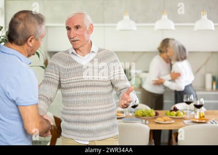 Zwei ältere Männer, die in der Küche die Hand schütteln Stockfoto