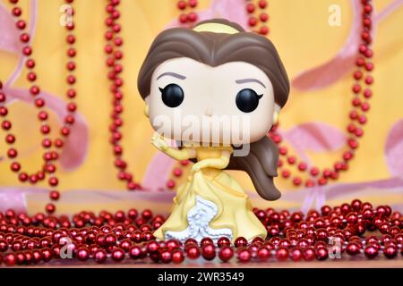 Funko Pop Actionfigur der Disney-Prinzessin Belle im gelben Kleid aus dem Animationsfilm Beauty and the Beast. Goldener rosa Vorhang, rote Halskette, fabelhaft. Stockfoto