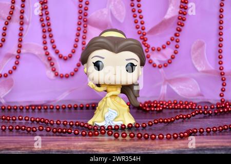 Funko Pop Actionfigur der Disney-Prinzessin Belle im gelben Kleid aus dem Animationsfilm Beauty and the Beast. Lila Vorhang, rote Halskette, fabelhaft. Stockfoto