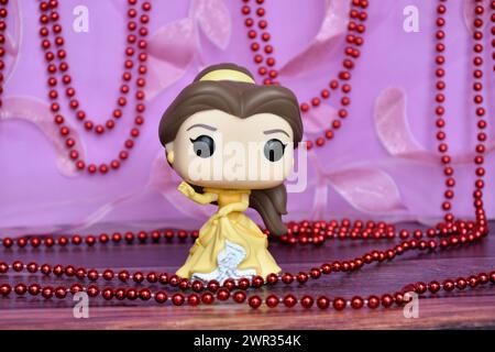 Funko Pop Actionfigur der Disney-Prinzessin Belle im gelben Kleid aus dem Animationsfilm Beauty and the Beast. Lila Vorhang, rote Halskette, fabelhaft. Stockfoto