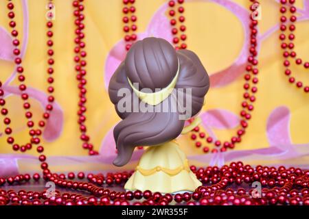 Funko Pop Actionfigur der Disney-Prinzessin Belle aus dem Zeichentrickfilm Beauty and the Beast. Rückansicht. Goldener rosa Vorhang, rote Halskette, fabelhafter Palast. Stockfoto