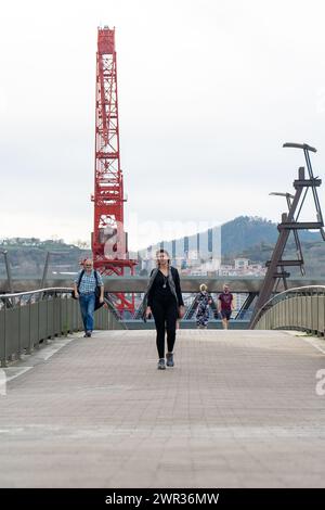 Menschen, die die Brücke über den Fluss Nervión überqueren, neben dem Guggenheim Museum in Bilbao-Baskenland-Spanien.13-3-2024 Stockfoto