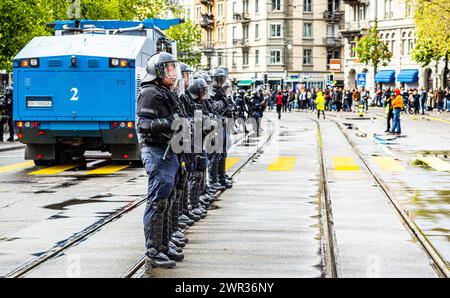 Die Polizisten der Stadtpolizei Zürich stehen in Schutzausrüstung hitner einem Wasserwerfer. (Zürich, Schweiz, 1. Mai 2023) Stockfoto