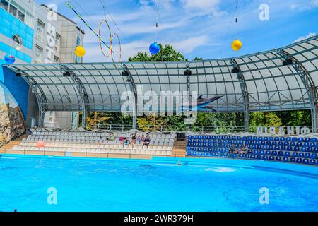 Delfine im Delphinarium. Kharkiv Dolphinarium Nemo, ein großer Delfin springt während einer Vorstellung hoch aus einem Pool. Das Stadion ist voller Menschen Stockfoto