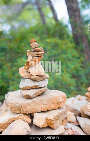 Sorgfältig gestapelte, leicht rote Steine bilden eine Steinfigur, Steinhügel, Wegmarke, Markierung im Wald, Wanderweg von Sant Elm zum alten Wachturm Stockfoto