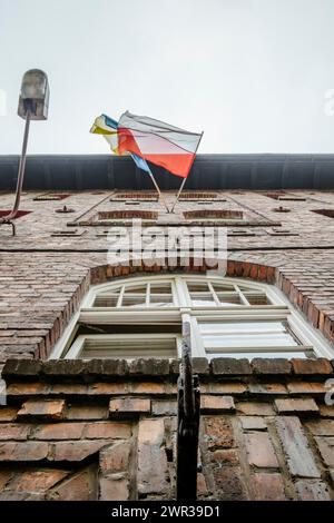 Polnische und ukrainische Flagge schwenken zusammen auf Ziegelhaus in Kattowitz Nikiszowiec, Südpolen Stockfoto