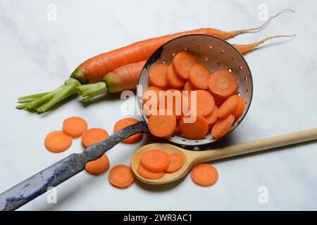 Karottenscheiben in Sieb und Holzlöffel, Daucus carota Stockfoto