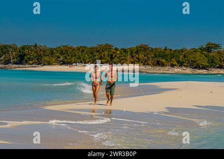 Ein Paar, das auf einem weißen Sandstrand auf der Insel Nosy Iranja in der Nähe von Nosy Be, Madagaskar spaziert Stockfoto