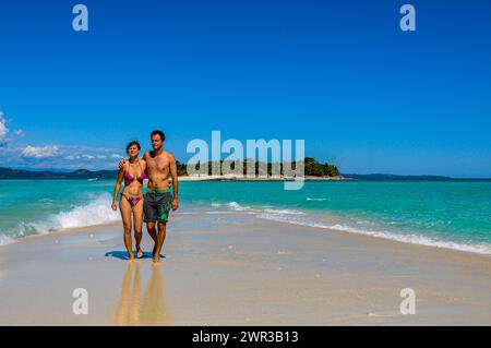 Ein Paar, das auf einem weißen Sandstrand auf der Insel Nosy Iranja in der Nähe von Nosy Be, Madagaskar spaziert Stockfoto