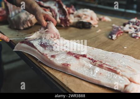 Fleischverarbeitungsbetrieb produziert verschiedene Fleischprodukte, der Metzger zerlegt ein Schwein. Hochwertige Fotos Stockfoto