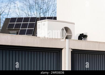 Wärmepumpe auf einem Garagendach eines Neubaus, im Hintergrund sind Solarpaneele auf Hausdächern, Monheim am Rhein, Nordrhein-Westfalen montiert Stockfoto