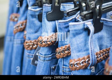 Blaue Jeans mit Gürtel am Kleiderbügel in einem Geschäft in der Schweiz Stockfoto