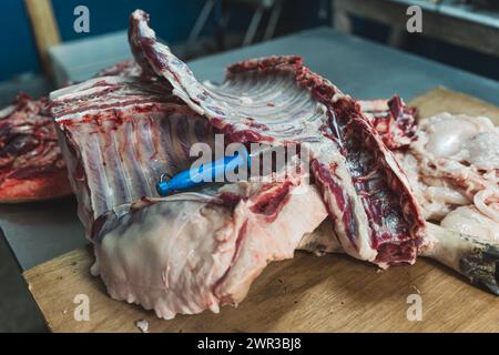 Große Schweinefleischscheiben und Rippchen und ein Messer auf dem Tisch, Schweineverarbeitung. Hochwertige Fotos Stockfoto