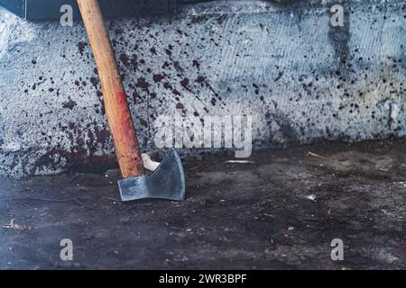 Eine Axt mit Bluttropfen vor einer Wand, die Schweine im Schlachthof zerschneidet. Hochwertige Fotos Stockfoto