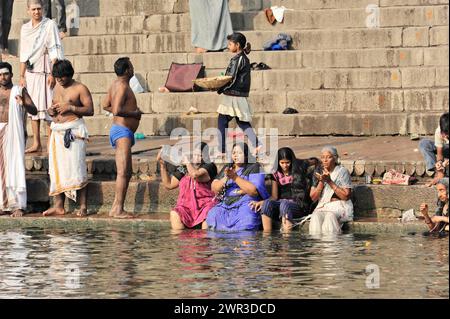 Gruppe von Menschen unterschiedlichen Alters in einem Fluss während des rituellen Badens mit traditioneller Kleidung, Varanasi, Uttar Pradesh, Indien Stockfoto