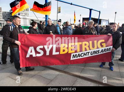 Die Teilnehmer der Demonstration Merkel muss weg halten ein Schild mit der Aufschrift Asylbetrug macht uns Arm. Demonstration von Rechtspopulisten und Rechtspopulisten Stockfoto