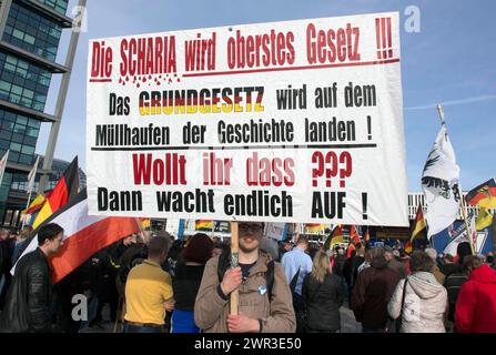 Ein Teilnehmer der Merkel muss weg-Demonstration hält ein Poster mit der Inschrift die Scharia wird oberstes Gesetz. Demonstration durch die rechte Seite Stockfoto