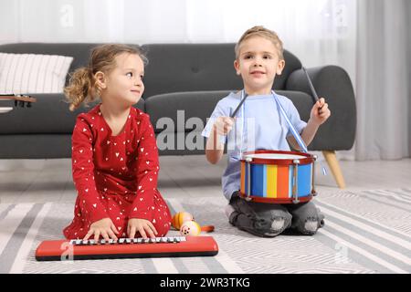 Kleine Kinder, die zu Hause Spielzeugmusikinstrumente spielen Stockfoto