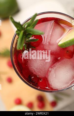 Leckerer Cranberry-Cocktail mit Rosmarin und Limette im Glas auf dem Tisch, Blick von oben Stockfoto