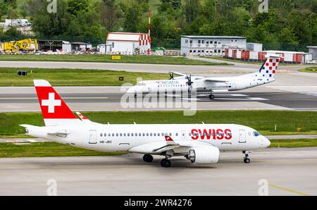 Auf der Starbahn 28 des Flughafen Zürich startete eine Bombardier Dash 8 Q400 von Croatia Airlines, davor rollt ein Airbus A220-100 von Swiss Internati Stockfoto