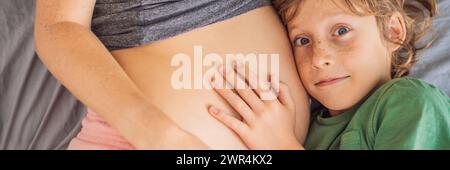 BANNER, LANGFORMAT Junge schöne schwangere Frau und ältester Sohn. Der süße Junge lehnte sein Ohr gegen den Bauch seiner Mutter. Ich erwarte ein Baby im Stockfoto