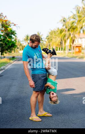 Vater Sohn, viel Spaß. Der Mann hält das Bein des Kindes auf dem Kopf. Freude Glück Kindheit Vaterschaft Freude Stockfoto