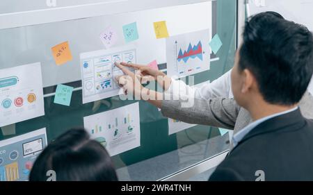 Ein Mann und eine Frau sehen sich ein Brett mit Grafiken und Zahlen an Stockfoto