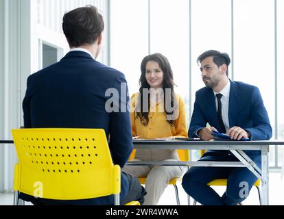 Das Konzept des Vorstellungsgesprächs. Vielfältiges HR-Team, das ein Vorstellungsgespräch mit einem Mann in einem Geschäftsbüro führt. Personalteam, das einen potenziellen Kandidaten interviewt. Stockfoto