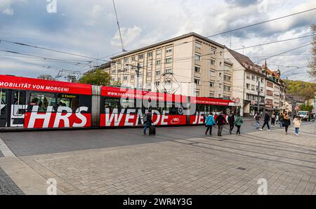 Eine Strassebahn der Linie 3 mit Zieldestionation Haid fährt am Platz der alten Synagoge vorbei. Auf der Seite steht der Schriftzug „Verkehrswende“. ( Stockfoto