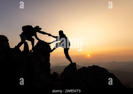 Silhouette der Teamarbeit zweier Wanderer, die sich auf dem Gipfel des Bergsteigerteams gegenseitig helfen. Teamwork Freundschaft Wandern hilft einander Vertrauen Assistentin Stockfoto