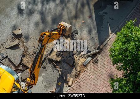 Bagger gräbt Asphalt, um eine Wasserstörung in einer Straße zu reparieren Stockfoto