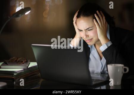 Nachts war ein Telearbeiter besorgt, der sich über den Laptop beschwerte Stockfoto