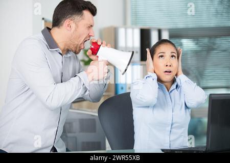 Der Boss schreit durch ein Megaphon nach Büroangestellten Stockfoto