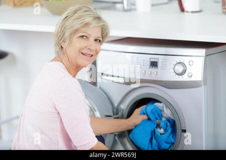 Ältere Frau laden Waschmaschine zu Hause Stockfoto