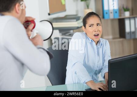 Der Boss ruft Büroangestellte durch ein Megaphon an Stockfoto