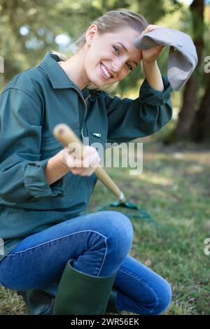 Müde junge Frau oder Gärtner mit Gartengeräten im Sommer Stockfoto