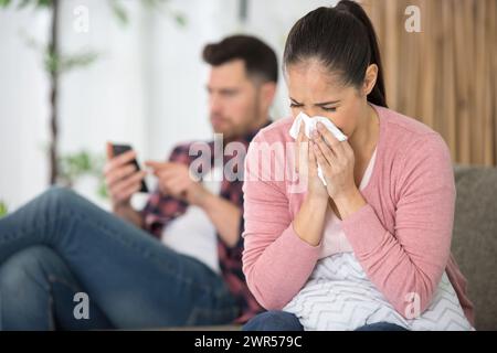 Eine junge Frau, die zu Hause ihre Nase in Gewebe bläst Stockfoto