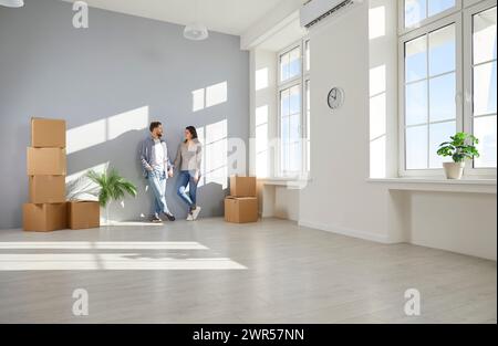 Glückliches junges Familienpaar zieht in ein neues, leeres, modernes Haus oder eine neue Wohnung Stockfoto