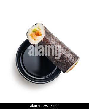 Ein Sushi-Brötchen, das ordentlich geschnitten und mit einer Beilage aus pikanter Sojasauce präsentiert wird. Das Sushi besteht aus frischem Fisch, Reis und Gemüse, das in Algen gerollt ist Stockfoto
