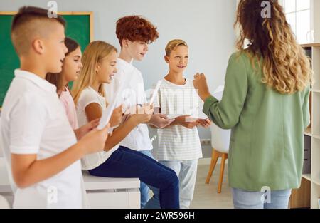 Schulkinder im Klassenzimmer mit Lehrer im Chor während des Musikunterrichts. Stockfoto