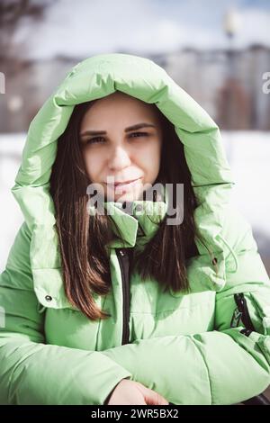 Eine Frau mit grüner Jacke steht auf dem schneebedeckten Boden, umgeben von weißen Landschaften Stockfoto