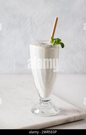 Indischer Salz mit Minzblättern und Kala-Namak auf weißem Hintergrund. Vertikales Format. Traditionelle gesunde Frische aus Joghurt, Wasser, Spr. Stockfoto