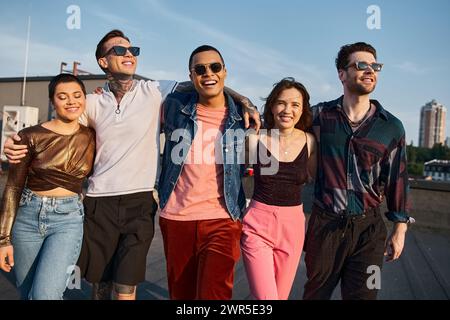 Glückliche multikulturelle Menschen in urbanen Outfits mit trendiger Sonnenbrille, die Spaß haben und vor der Kamera lächeln Stockfoto