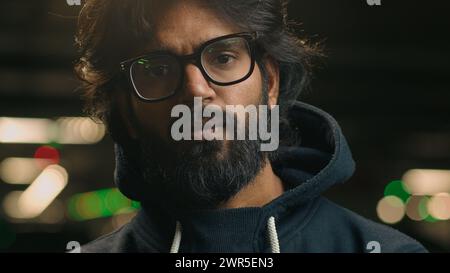 Nahaufnahme Porträt ernsthaft selbstbewusster Hipster Muslim Guy Arabian Mann Inder bärtiger Mann in dunkler Nacht Stadt städtischer Parkplatz unterirdisch aussehend Stockfoto