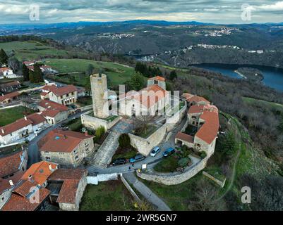 Aus der Vogelperspektive auf die kleine mittelalterliche Stadt Chambles mit dem Turm und der Steinkirche. Im Hintergrund die Schluchten de la Loire. Frankreich Stockfoto