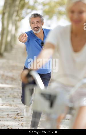 Senior-Mann, der hinter einer Radfreundin in der Stadt her ist Stockfoto